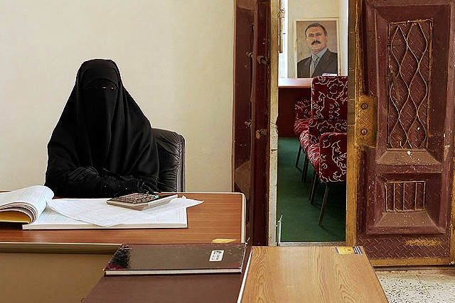 Υεμένη, 2006. Η Elham Abdul Waze Nuzzi εργάζεται στο περιφερειακό γραφείο του Υπουργείου αλληλεγγύης στην πόλη της Al-Mahwit. Μηνιαίος μισθός: 12.000 Ριάλ (€ 46). Στο βάθος διακρίνεται ένα πορτρέτο του Προέδρου της Υεμένης Saleh.
