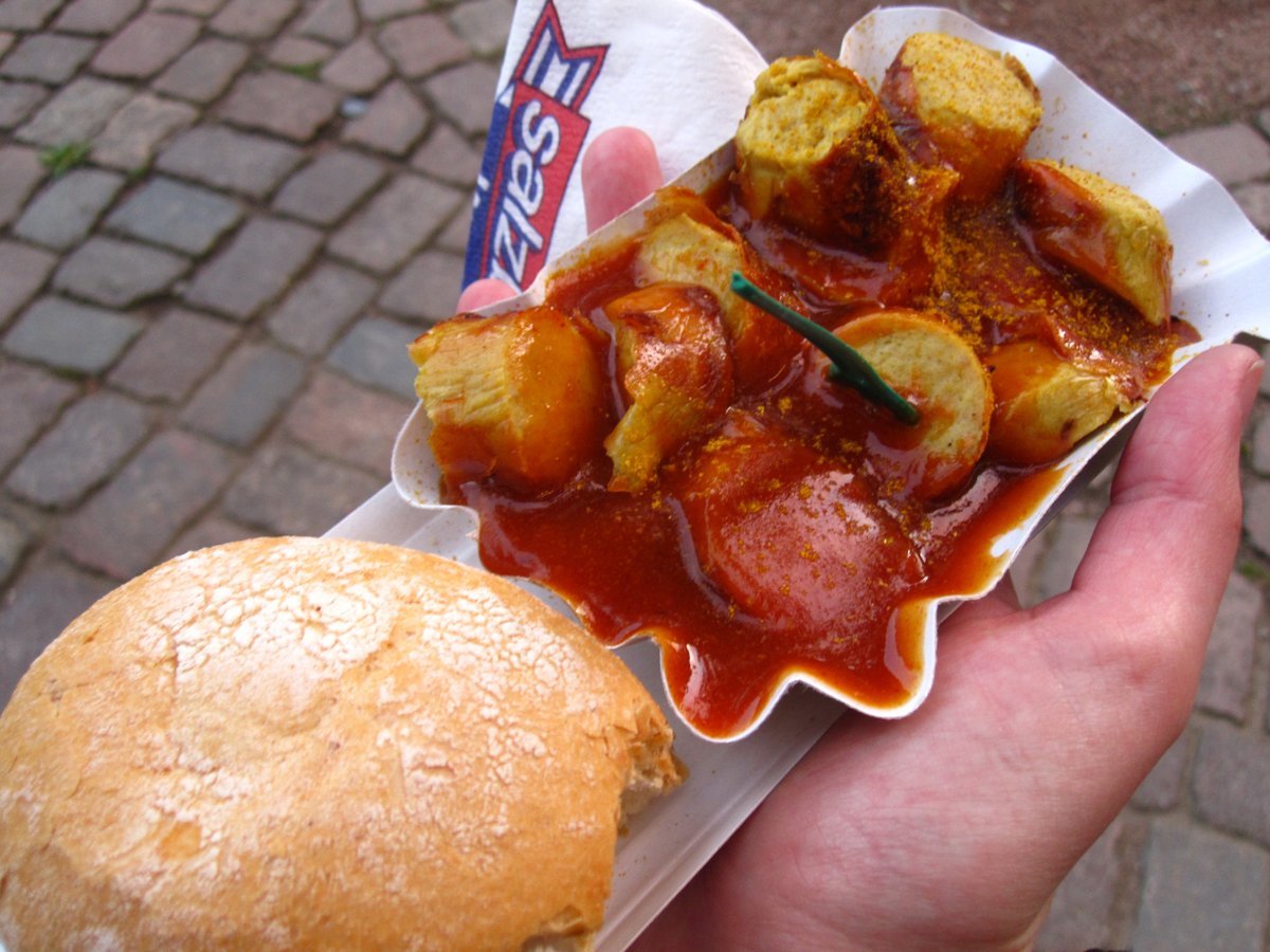 sample-berlins-iconic-street-food-currywurst-pork-sausage-thats-cut-into-slices-and-doused-with-curry-ketchup-its-served-with-a-fresh-roll-to-sop-up-the-delicious-sauce-berliners-love-konnopke-imbiss-in-the-neighborhood-o